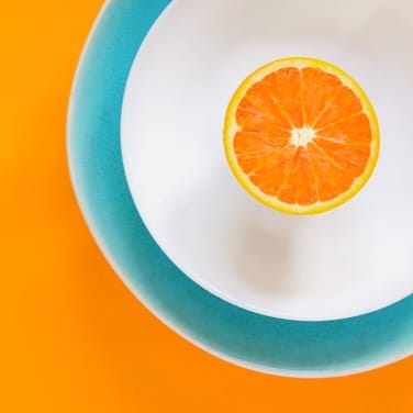 one slice orange over the white plate  with background dark yellow